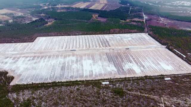Drone reveals vast snowy peat landscape bordered by pine forest in Cenu Bog