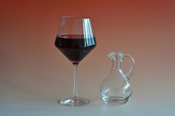 Glaskaraffe mit Rotwein und ein Rotweinglas vor einem bunten Hintergrund