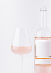 Enjoying a glass of rose wine with a bottle on a simple background