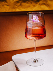 Refreshing cocktail with flower garnish sits on a table in warm setting