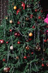 Close-up of a Christmas tree with red baubles and silver bead garlands