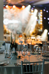 Wide view of banquet hall with tables, chairs, and stage lighting
