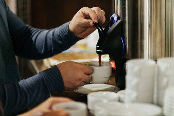Man pouring coffee from a dispenser into a cup