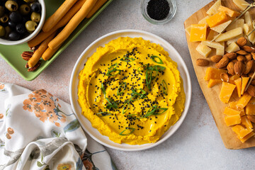 Gather around a colorful charcuterie board featuring turmeric hummus, cheese, nuts, and olives. This delightful spread invites friends to share tasty bites and enjoy each other company