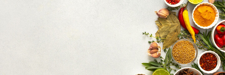 A mix of dried herbs and spices laid out on a gray background, highlighting natural flavors and culinary essentials, top view and copy space, banner