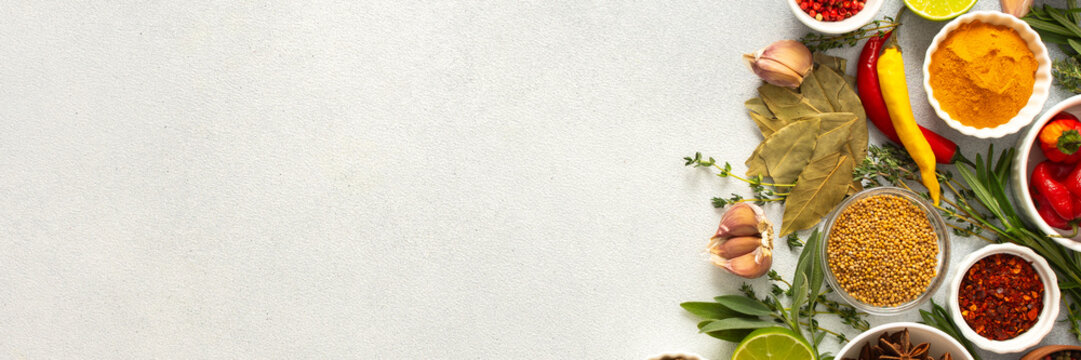 A mix of dried herbs and spices laid out on a gray background, highlighting natural flavors and culinary essentials, top view and copy space, banner