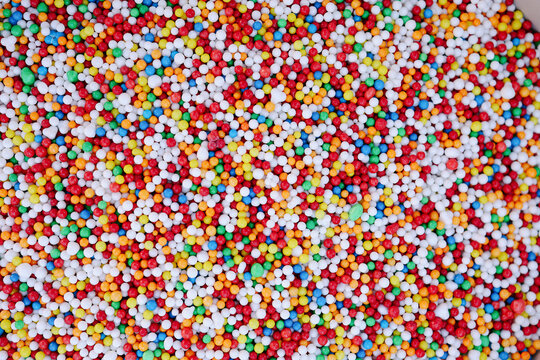 Full frame overhead background of colorful, tiny spherical candy sprinkles
