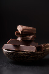 Small pieces of chocolate bars are arranged on a black background