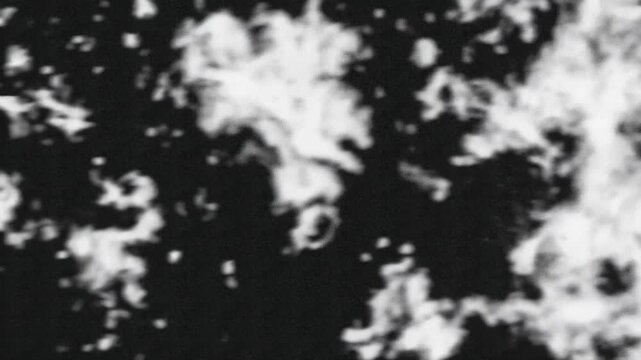 A black and white abstract image with contrasting shapes and textures resembling clouds or rocky surfaces.