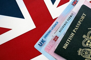 United Kingdom driving license with passport and residence permit card on UK flag close up