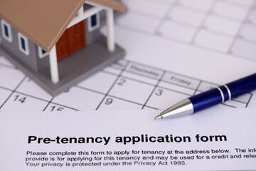 Generic toy house and Pre tenancy application form with pen on table close up