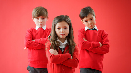 Group Of Elementary School Pupils Wearing Uniform Against Red Studio Background