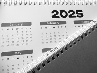 Top view of 2025 calendar, notepad, and pen on desk.