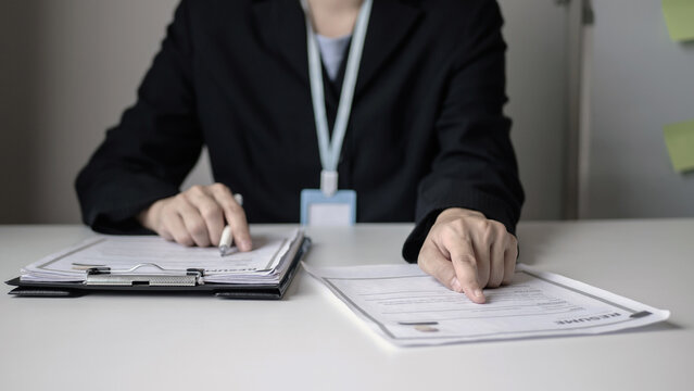 Businesswoman reading resume of new job applicant, reviewing history and evaluating documents before interviewing new employee. Recruitment concept