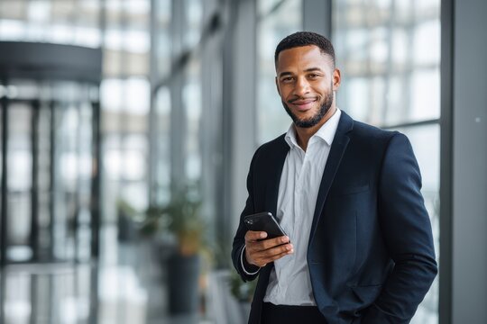 Young professional looking at a smartphone in a minimalist glass-walled office setting