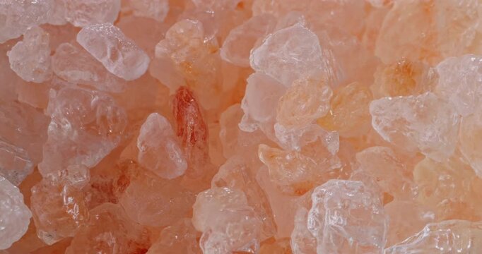 Pink Himalayan Salt Crystals Seamless Loop. Close-up macro view of coarse rose-colored Himalayan salt grains gently sparkling under soft lighting.  