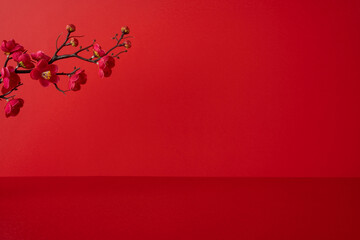 Side view of a vivid red backdrop featuring a branch of pink plum blossoms, conveying festive...