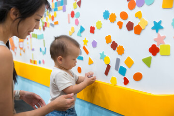 Mother and baby playing with magnets on whiteboard at playhouse