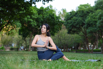 Woman practicing yoga exercise outdoors at green park