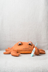 Toy crab with thermometer lays covered with baby blanket- top view. Children Healthcare concept photo.