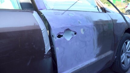An experienced technician repairs a damaged car door in a garage. The process involves cutting, patching and refinishing to restore the door's appearance.