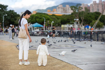 Young mother carrying baby to see birds in park