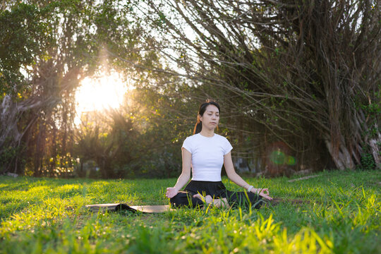Woman practicing peaceful meditation on grass outdoors