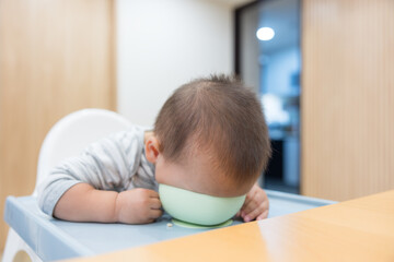 Baby putting head inside bowl at home