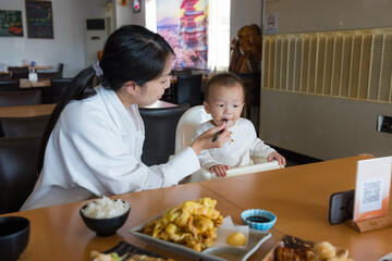 Mother feeding her baby at family restaurant table