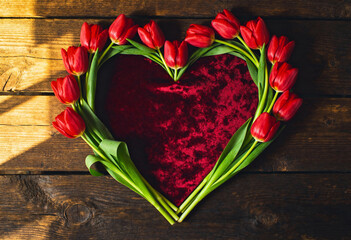 Tulips forming heart shape on dark wooden background, perfect for a Valentines Day or mothers day greeting card design
