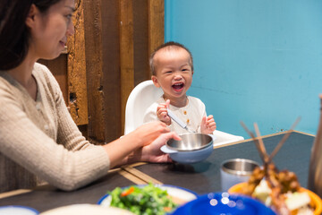 Mother feeding her happy baby at restaurant