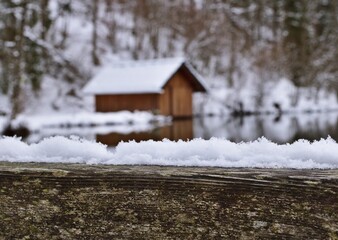 Holzzaun mit Schnee und Bootshaus am Almsee, Österreich