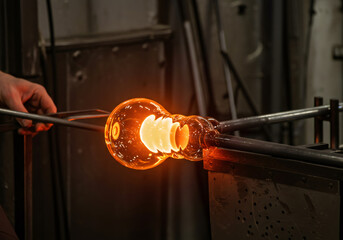 Man glass blower shaping molten glass art with a blowtorch flame. Craftsmanship and traditional glass blowing