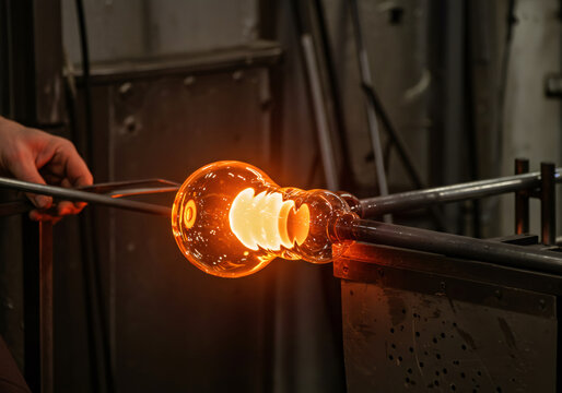 Man glass blower shaping molten glass art with a blowtorch flame. Craftsmanship and traditional glass blowing - Powered by Adobe