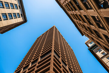 Modern skyscraper rising against a clear blue sky, showcasing bold urban architecture and geometric design.