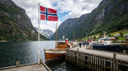 A vibrant flag of norway flutters near a rustic pier with scenic fjord cruise boats.