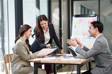 Group of Asian businesspeople sits down for a business investment planning meeting.	