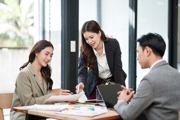 Group of Asian businesspeople sits down for a business investment planning meeting.