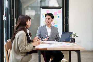 Group of Asian businesspeople sits down for a business investment planning meeting.	