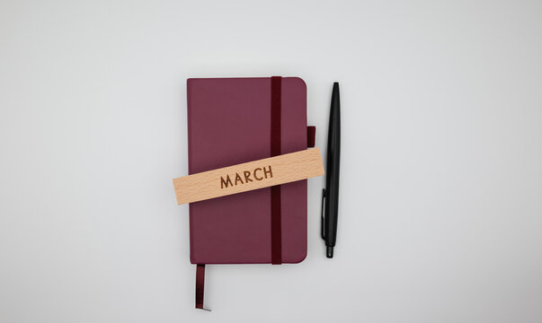 Clean workspace flat lay with planner, pen, and wooden block labeled March. Ideal for spring planning, productivity, and scheduling content.