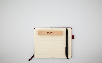 Minimalist flat lay with planner, pen and a wooden block labeled May. Perfect for productivity, planning, and seasonal spring themes.