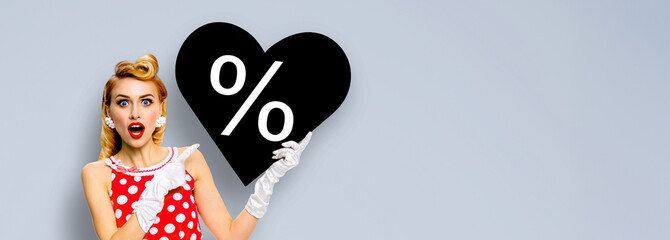 Black Friday sale ad concept - pinup beautiful woman show heart shape paper banner with percentage percent % discount sign. Pin up cute girl. Retro fashion vintage. Isolated gray grey background