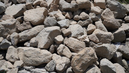 Close-up photograph of a pile of large gray and beige rocks with rough, weathered texture, stones concept.