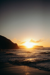 Dramatic Ocean Sunset with Waves and Silhouetted Cliffs