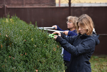 Mother and yound adult daughter trimming a garden edge