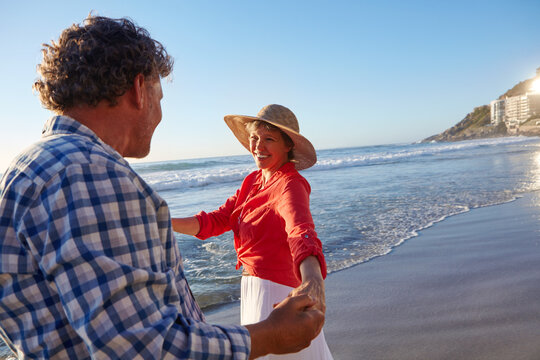 Smile, mature couple and dancing on beach for romantic date, travel adventure and summer vacation. Love, happy people and holding hands with movement at seaside for holiday getaway and mockup space
