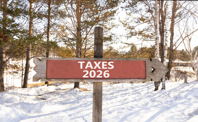 Taxes 2026 new year symbol. Concept words Taxes 2026 on beautiful wooden road sign. Beautiful winter forest background. Business and taxes 2026 new year concept. Copy space.