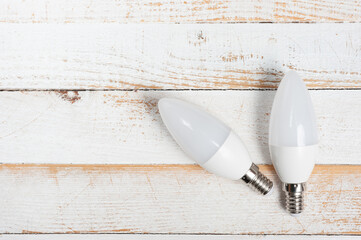 Two LED lamps with E14 sockets lying on a wooden surface.