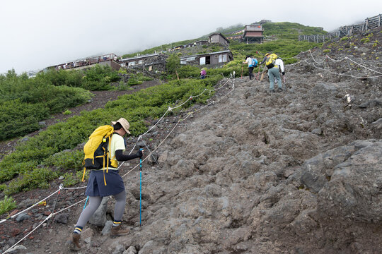 On Mount Fuji, Kitayama, Fujinomiya, Shizuoka, Japan, Hikers climbing rocky mountain trail with backpacks and trekking poles
