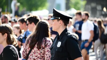 Police officer monitoring a crowded outdoor event in daylight, public safety and crowd control with community presence during city gathering